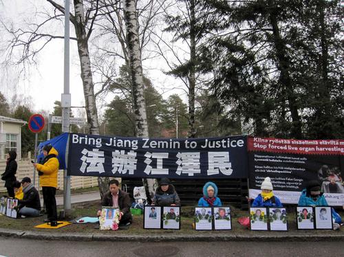 二零一六年四月二十五日，吴志平在芬兰中领馆前手捧着母亲遗像，要求法办恶首江泽民。